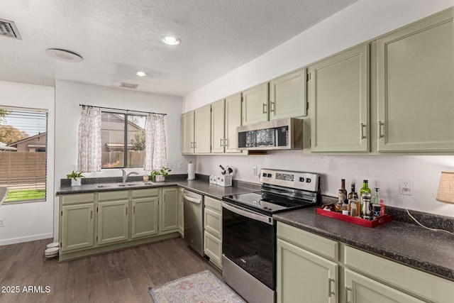 kitchen featuring green cabinets, sink, dark wood-type flooring, and appliances with stainless steel finishes