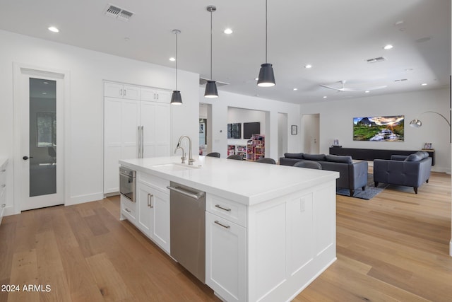 kitchen featuring an island with sink, light hardwood / wood-style flooring, sink, and white cabinets