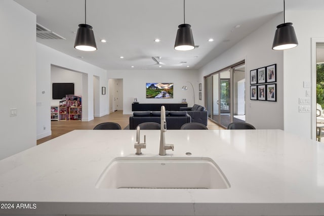 kitchen with light wood-type flooring, decorative light fixtures, sink, and ceiling fan