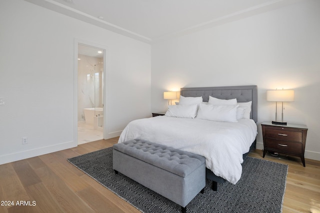 bedroom with light wood-type flooring and ensuite bath