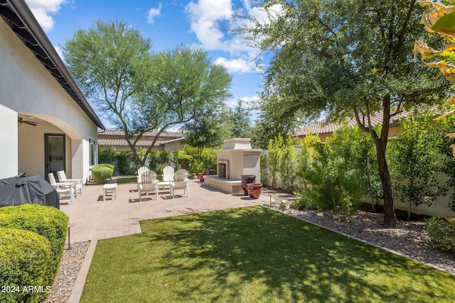 view of yard featuring exterior fireplace and a patio area