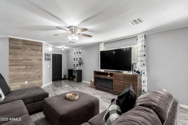 living room featuring ceiling fan, light hardwood / wood-style floors, and crown molding