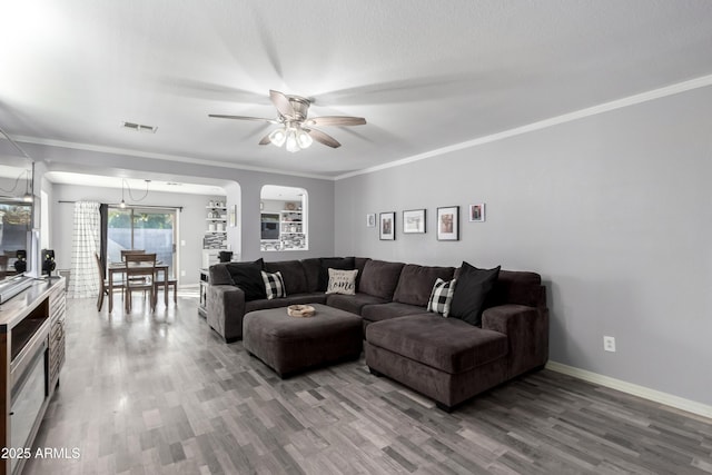 living room featuring hardwood / wood-style flooring, ceiling fan with notable chandelier, and ornamental molding