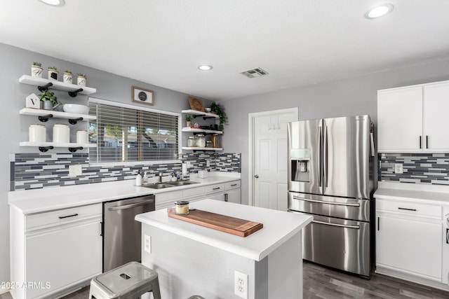 kitchen with white cabinetry, sink, stainless steel appliances, decorative backsplash, and a kitchen island