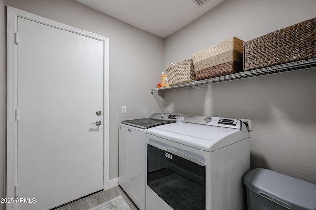 clothes washing area featuring washing machine and dryer and light hardwood / wood-style flooring