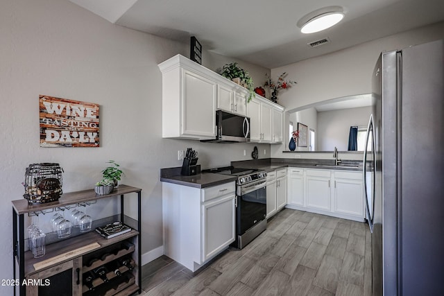 kitchen with stainless steel appliances, sink, light hardwood / wood-style flooring, and white cabinets