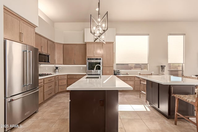 kitchen with light tile patterned floors, stainless steel appliances, a breakfast bar, and a center island with sink