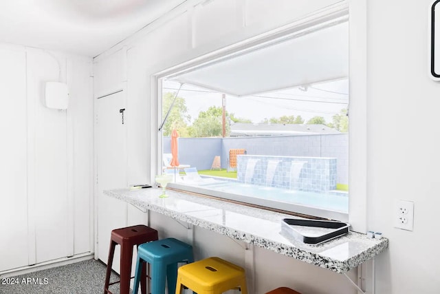 interior space featuring white cabinets, a breakfast bar, and light stone countertops