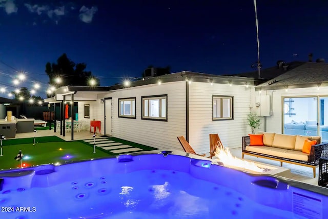 back house at twilight featuring a patio, an outdoor living space with a fire pit, and an outdoor hot tub