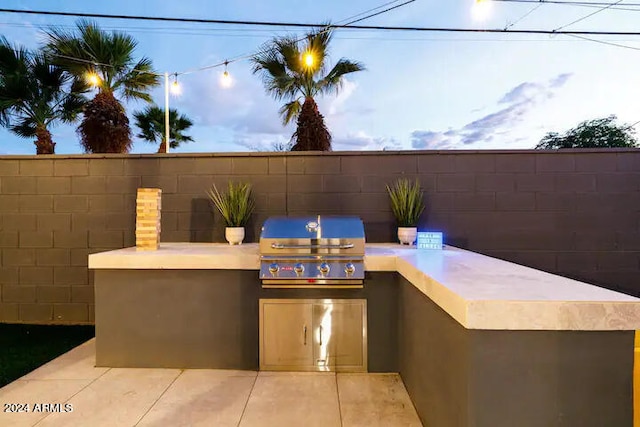 patio terrace at dusk featuring a grill and area for grilling