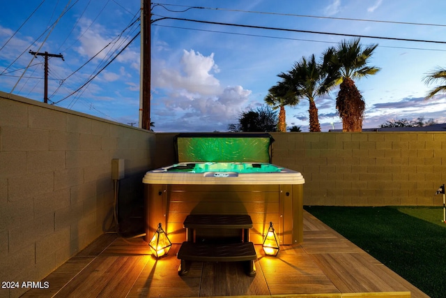 patio terrace at dusk with a wooden deck and a hot tub