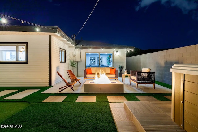 back house at night with a patio area and an outdoor living space with a fire pit