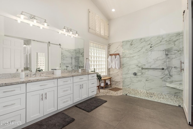 bathroom featuring double vanity, high vaulted ceiling, a sink, and a marble finish shower