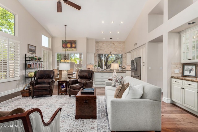living area featuring ceiling fan, high vaulted ceiling, recessed lighting, baseboards, and wood finished floors