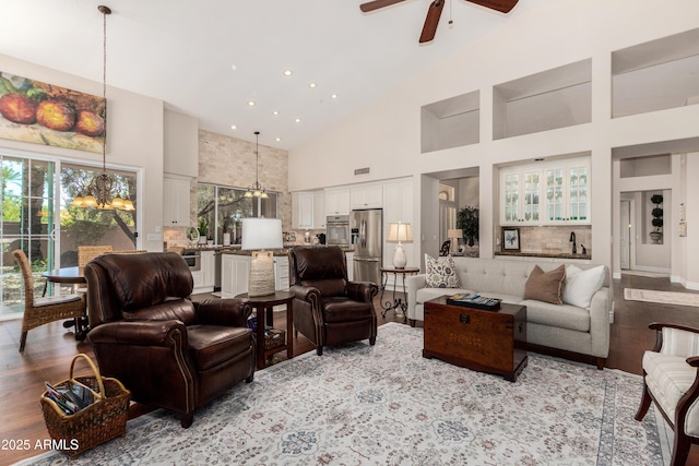 living room with high vaulted ceiling, visible vents, a wealth of natural light, and ceiling fan with notable chandelier