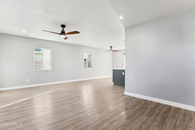 unfurnished living room featuring hardwood / wood-style floors, ceiling fan, and a healthy amount of sunlight