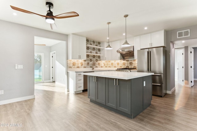 kitchen featuring a center island, stainless steel fridge, white cabinetry, and tasteful backsplash