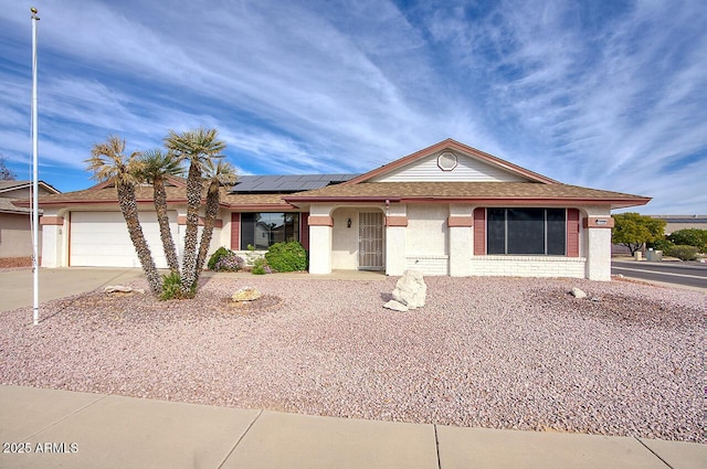 ranch-style house featuring a garage and solar panels