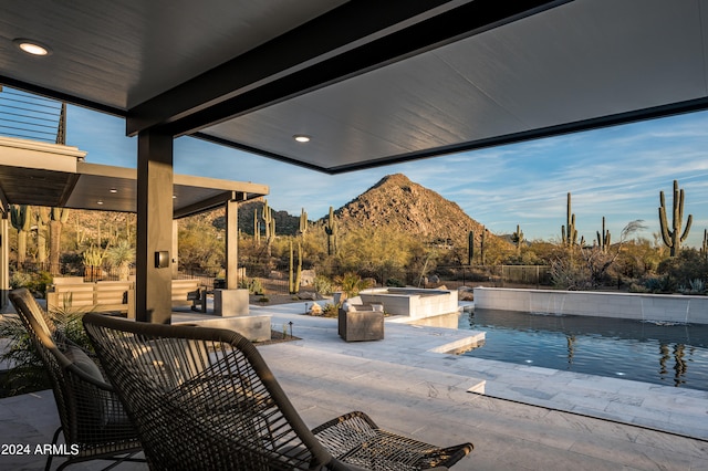 view of patio / terrace with a swimming pool with hot tub and a mountain view