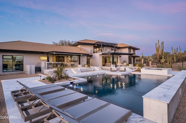 pool at dusk with an in ground hot tub, an outdoor living space, and a patio area