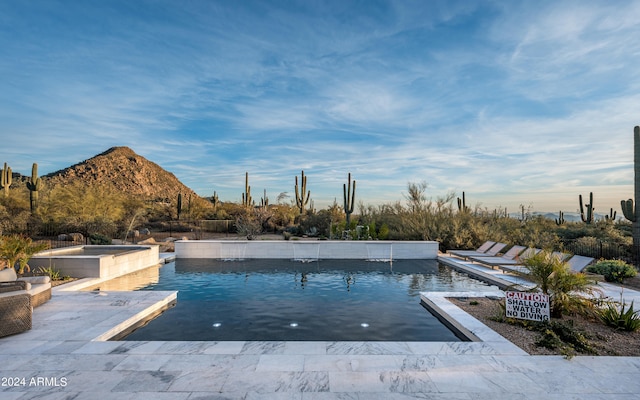 view of swimming pool with pool water feature and a mountain view