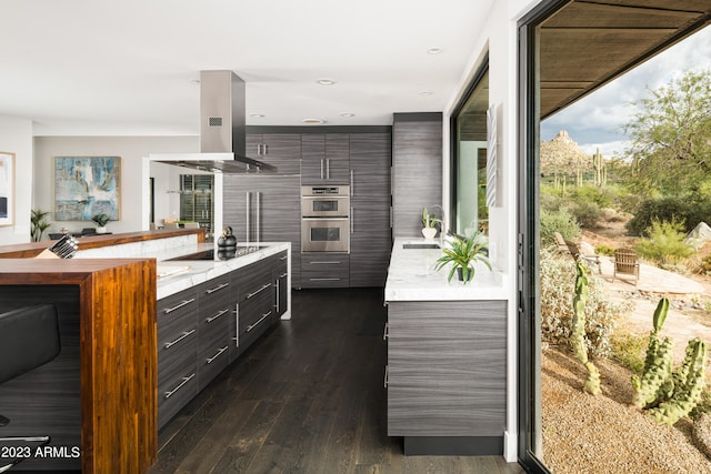 kitchen with stainless steel double oven, dark hardwood / wood-style flooring, black electric cooktop, and island range hood