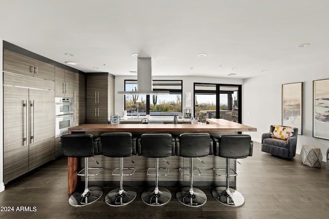 kitchen with dark hardwood / wood-style floors, a breakfast bar area, appliances with stainless steel finishes, and wood counters