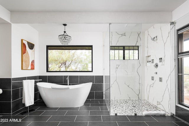 bathroom featuring tile flooring, tiled shower, a wealth of natural light, and tile walls