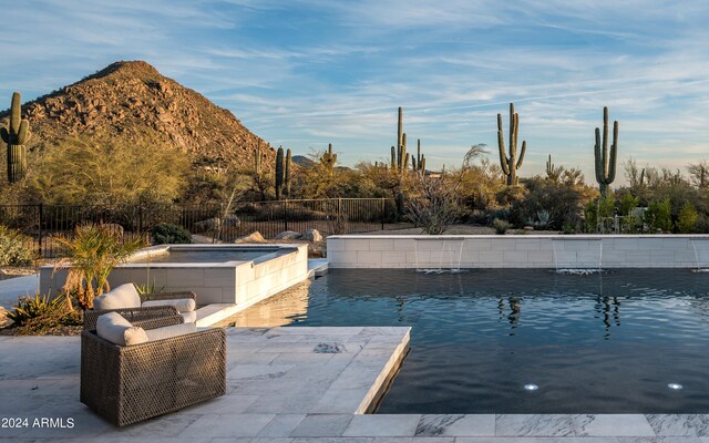 view of swimming pool with a patio area, pool water feature, a mountain view, and an outdoor hot tub