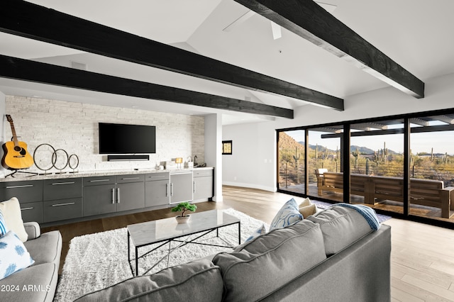 living room featuring ceiling fan, light wood-type flooring, and beamed ceiling