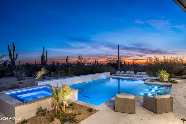 pool at dusk featuring a patio and an in ground hot tub