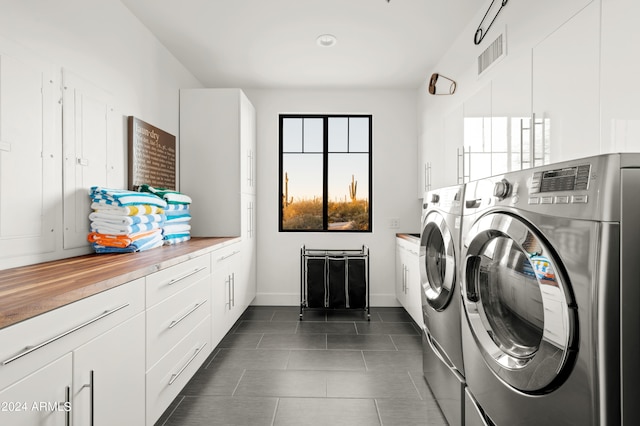 laundry room featuring washer and dryer, dark tile floors, and cabinets