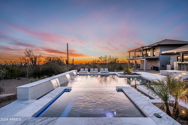 pool at dusk featuring a patio