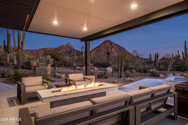 patio terrace at dusk with a mountain view and an outdoor living space with a fire pit