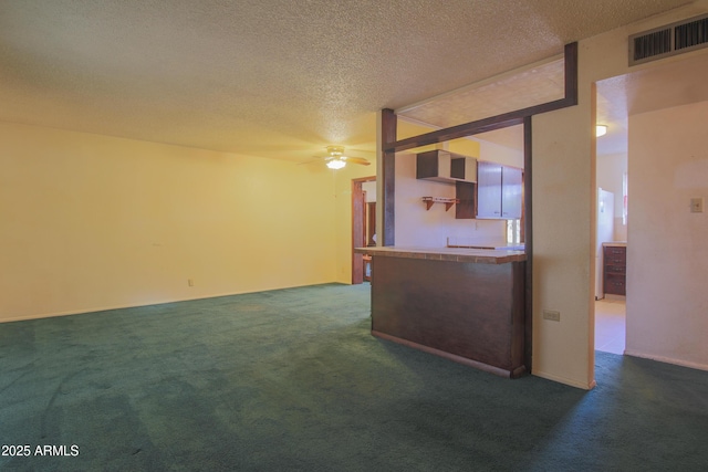 unfurnished living room featuring dark colored carpet, ceiling fan, and a textured ceiling