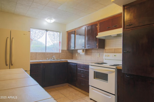 kitchen with light tile patterned flooring, sink, decorative backsplash, fridge, and white range with electric cooktop