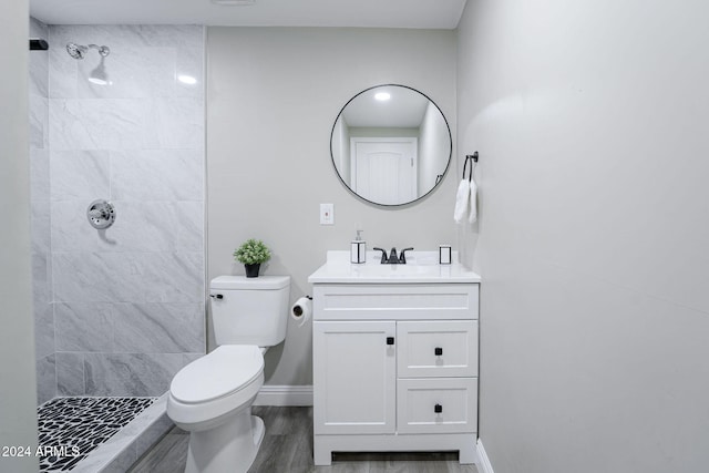 bathroom with vanity, a tile shower, hardwood / wood-style flooring, and toilet