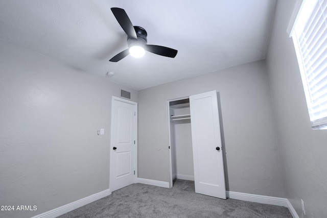 unfurnished bedroom featuring light colored carpet, multiple windows, a closet, and ceiling fan