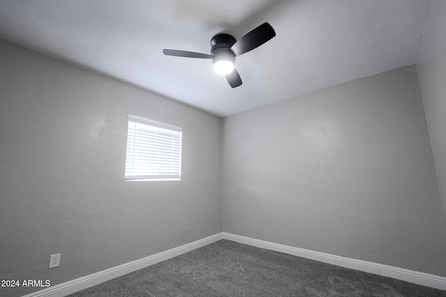 empty room featuring dark carpet and ceiling fan