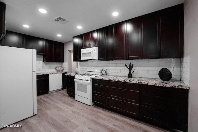 kitchen featuring light stone countertops, decorative backsplash, light hardwood / wood-style flooring, and white appliances