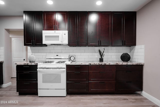 kitchen with white appliances, light stone counters, decorative backsplash, and light wood-type flooring