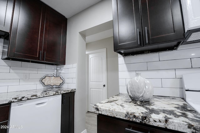 kitchen with dark brown cabinetry, backsplash, light stone countertops, and dishwasher