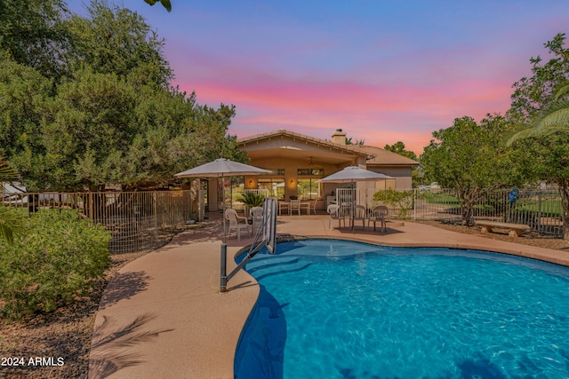 pool at dusk featuring a gazebo and a patio area