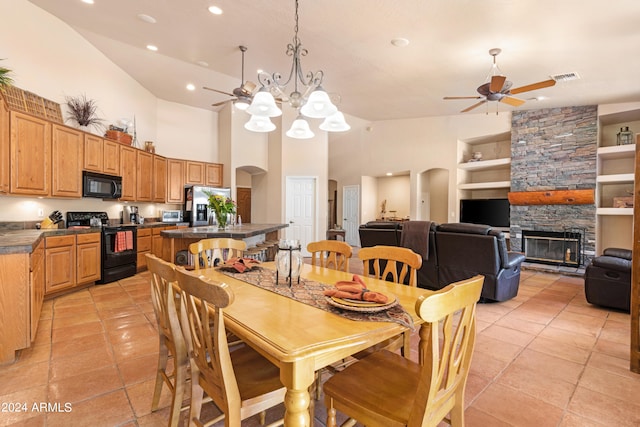 tiled dining space with high vaulted ceiling, built in shelves, ceiling fan with notable chandelier, and a stone fireplace