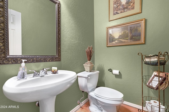 bathroom with toilet, sink, and tile patterned floors