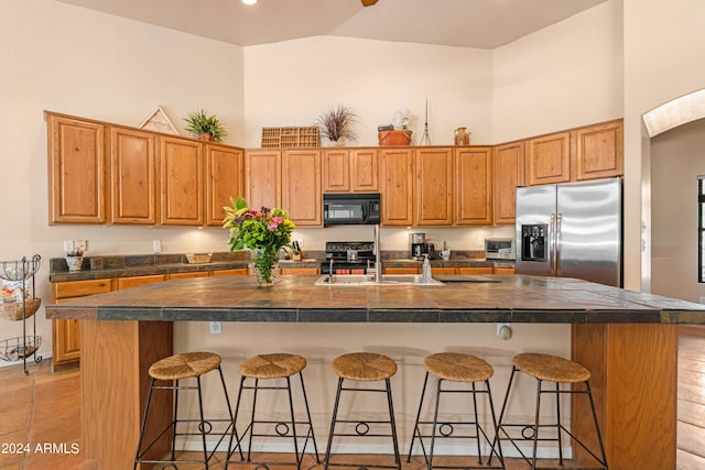 kitchen with an island with sink, a breakfast bar area, and stainless steel fridge