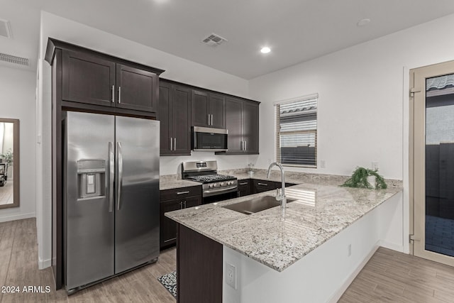 kitchen featuring sink, light hardwood / wood-style flooring, kitchen peninsula, dark brown cabinets, and appliances with stainless steel finishes