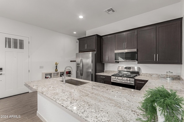 kitchen featuring kitchen peninsula, dark brown cabinetry, sink, and stainless steel appliances