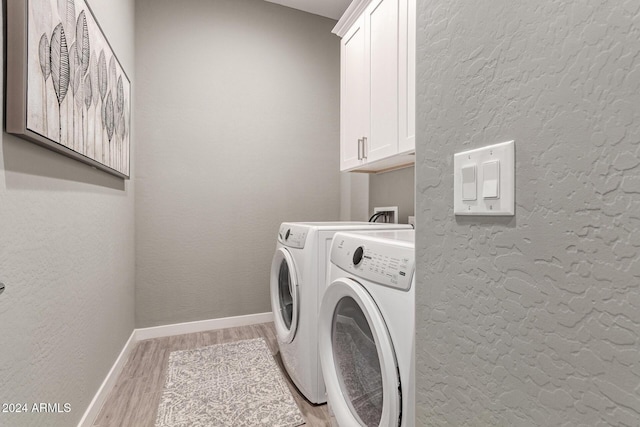 laundry room featuring light hardwood / wood-style floors, cabinets, and washing machine and dryer