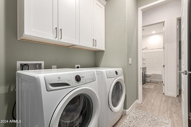 laundry area with cabinets, separate washer and dryer, and light hardwood / wood-style flooring